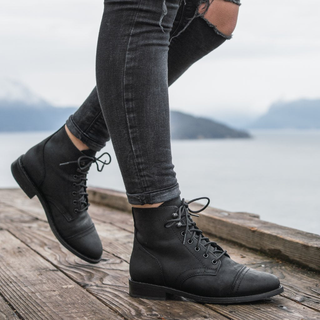 Black matte leather lace-up ankle boots on wearer, rounded toe and ankle height