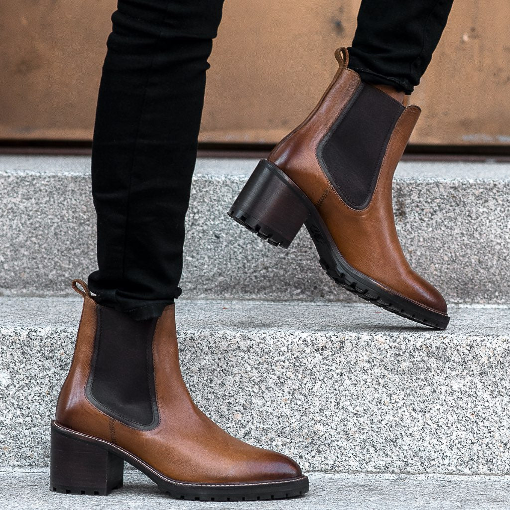 Brown chelsea boots on feet with dark elastic panels and block heel