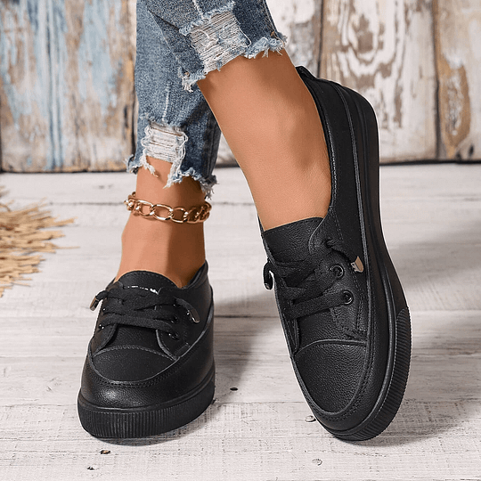 Women’s black chunky platform lace-up sneakers in faux leather, angled side view on feet.