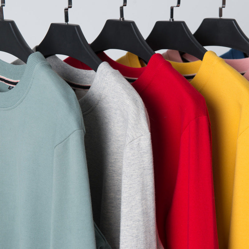 Round-neck cotton sweaters on hangers in light blue, grey, red, and yellow tones