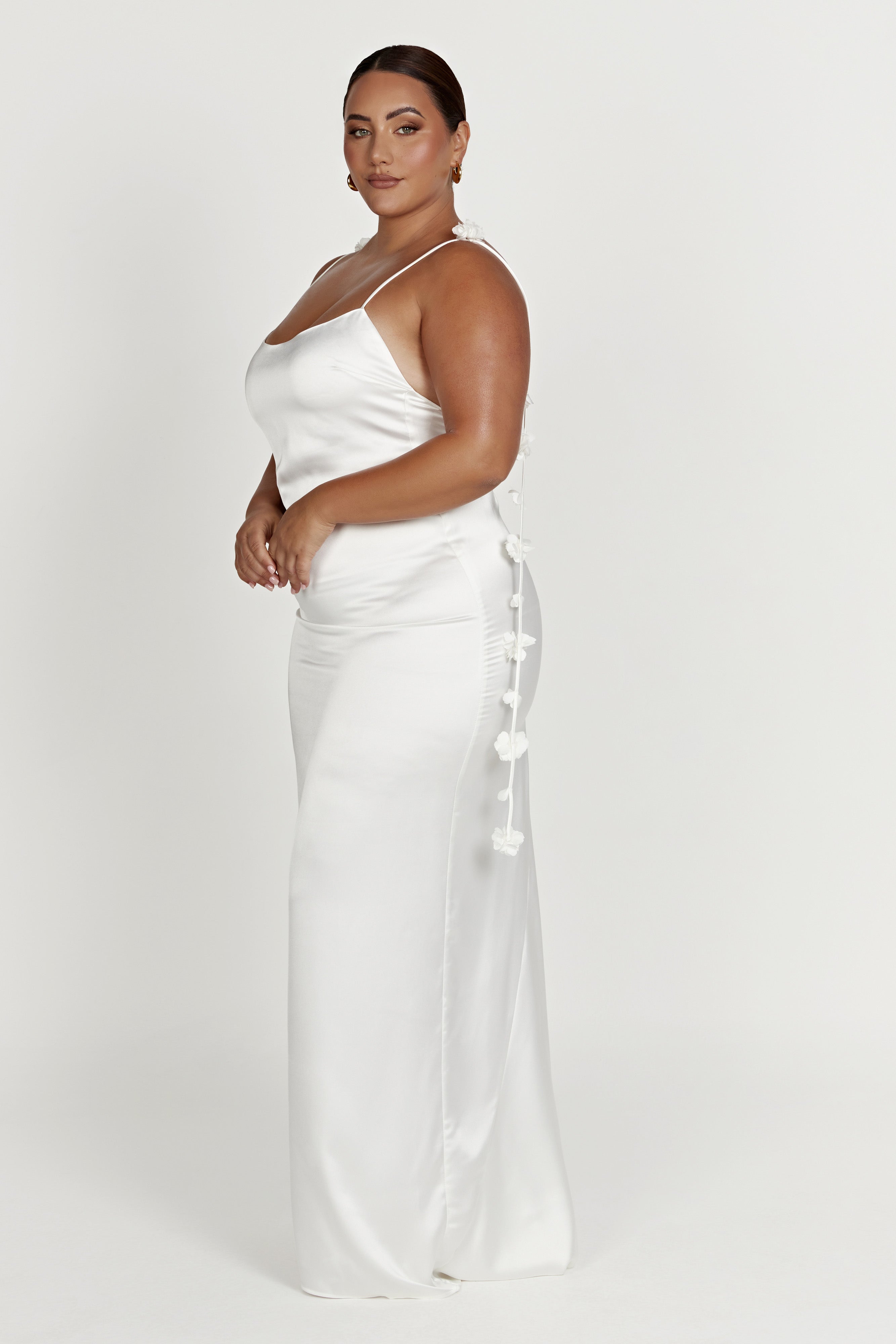 White satin slip maxi dress with floral strap accents in a side pose