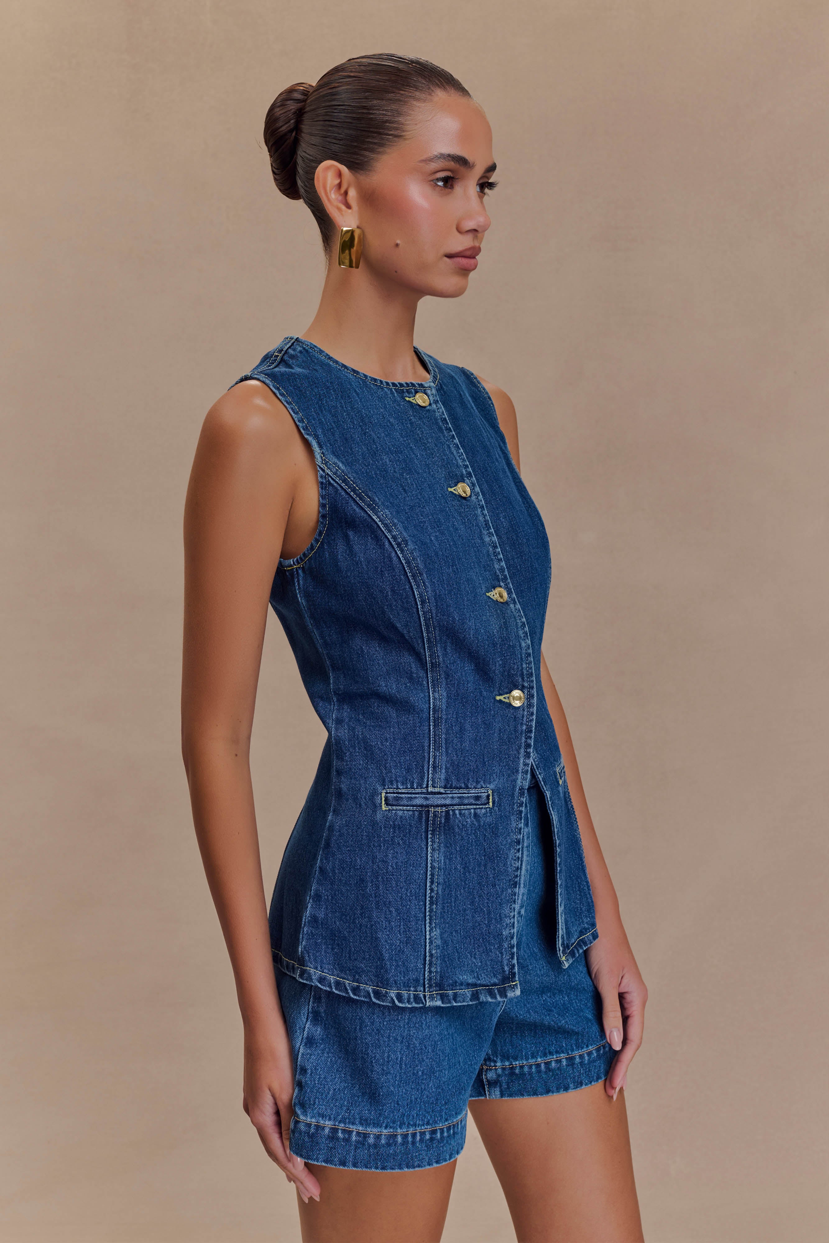 Blue denim sleeveless vest with gold buttons and tailored patch pockets