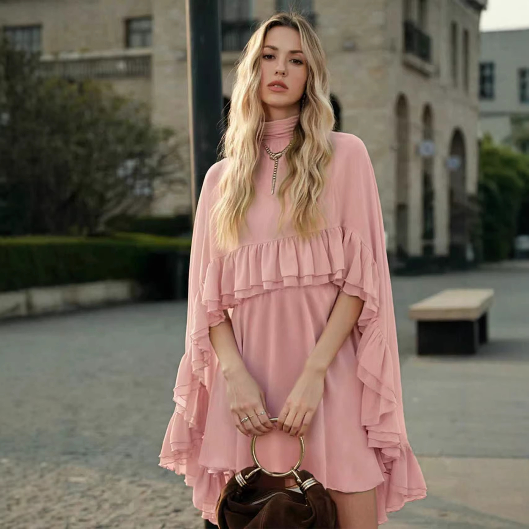 Blush pink chiffon mini dress with high neck, cape sleeves, and tiered ruffle skirt