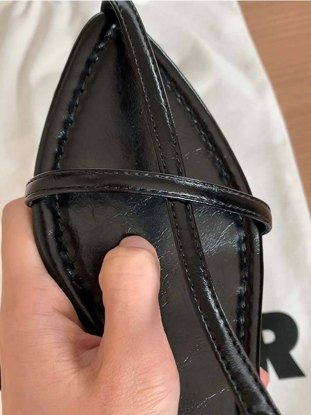 Close-up of black faux leather pointed toe T-strap flat with ankle strap