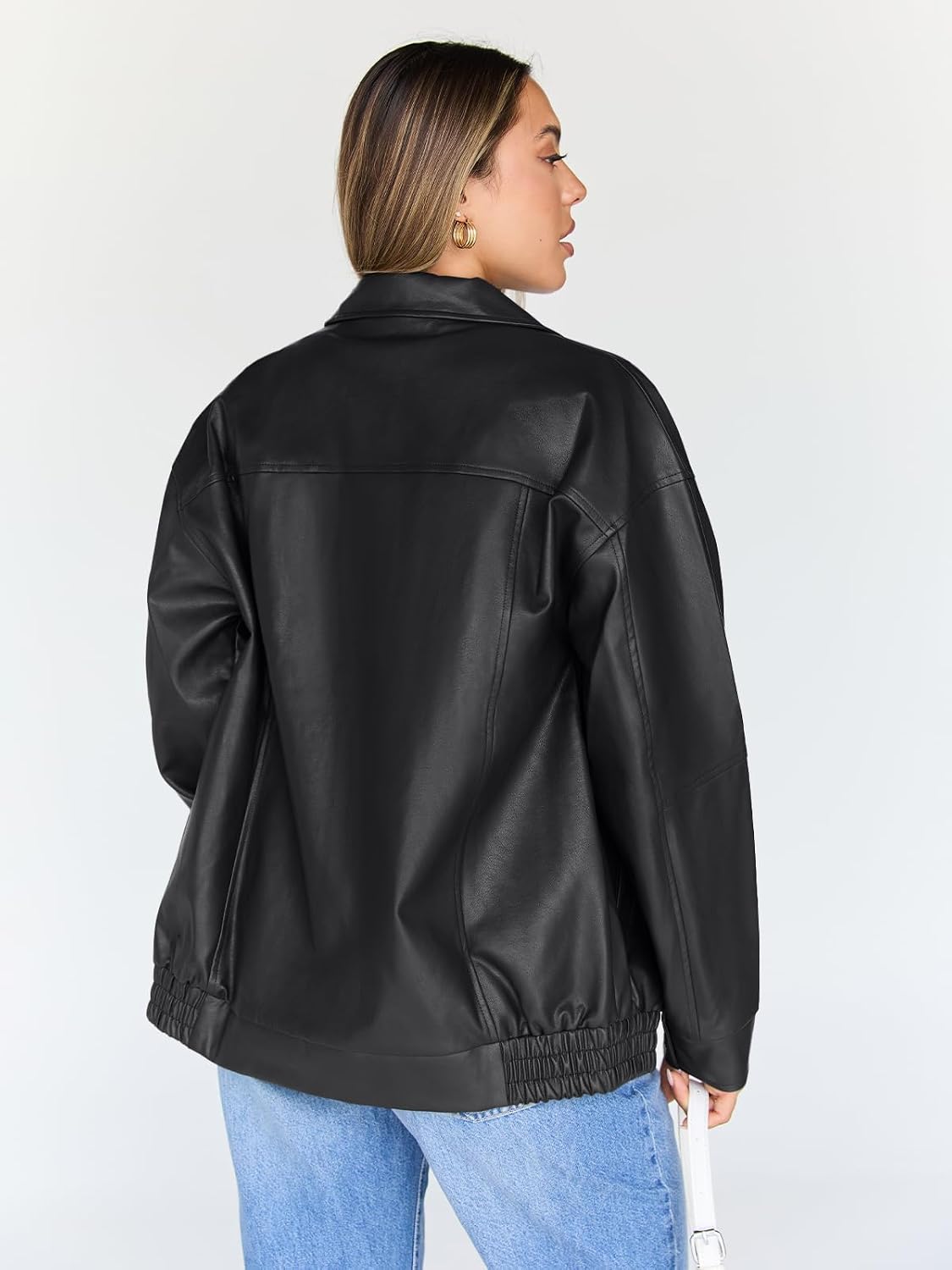 Back of a black oversized leather bomber jacket with a yoke seam and gathered hem