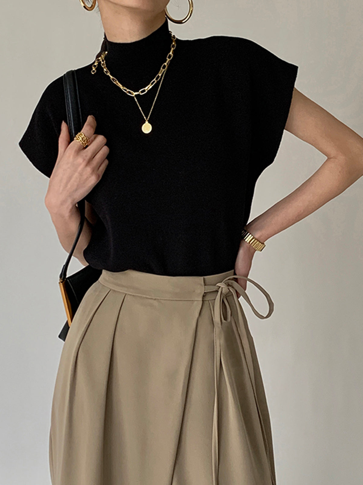Black sleeveless mock neck knit top with short sleeves and relaxed hemline