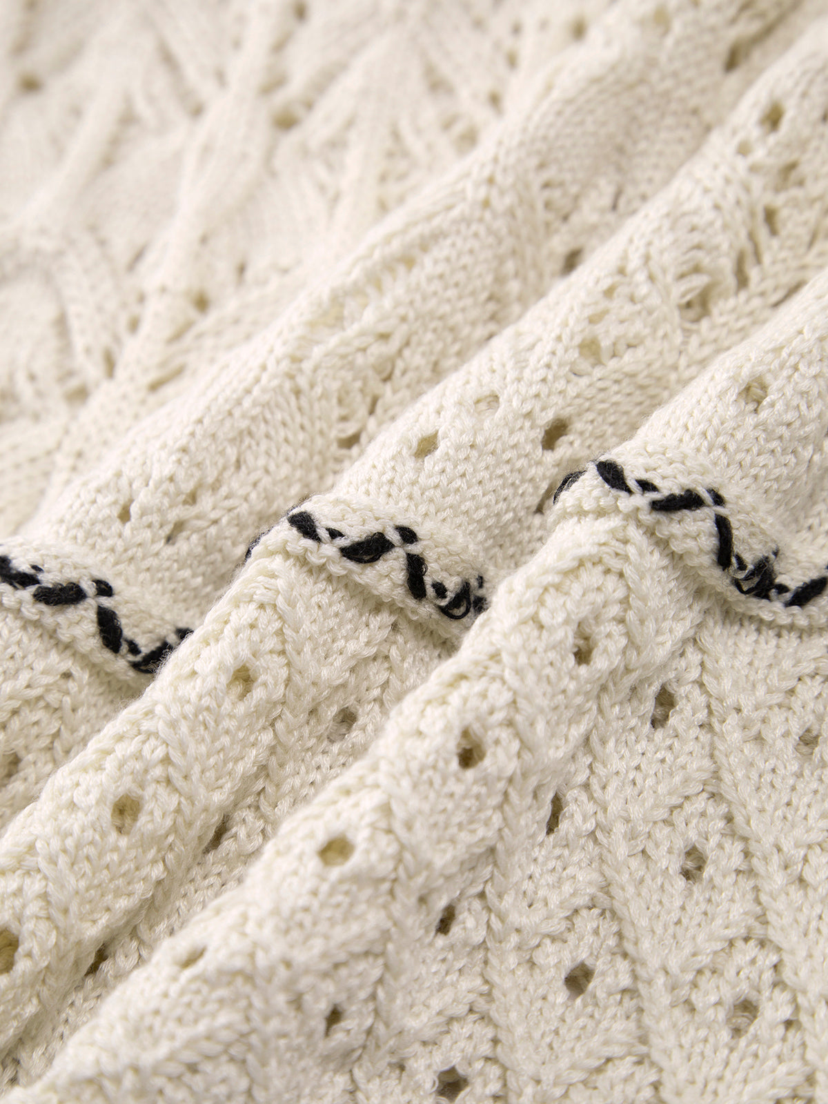 Off-white crochet knit close-up with black contrast stripe trim detail