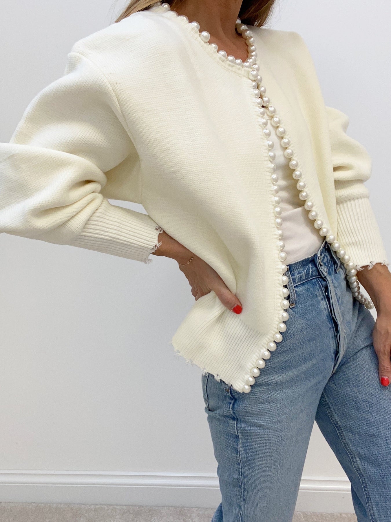 Women’s cream cardigan with pearl button trim along open front and ribbed cuffs