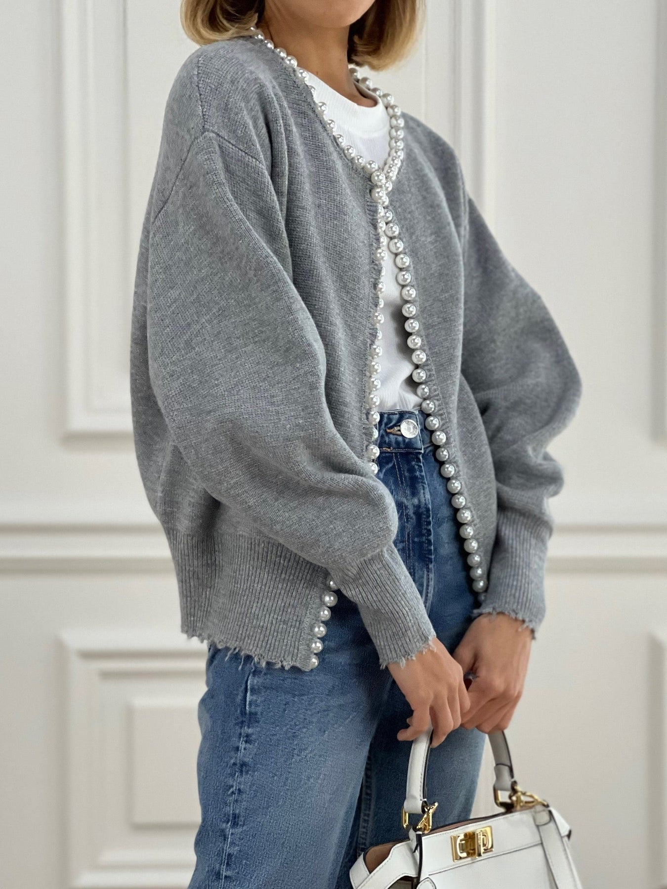 Women's grey knit cardigan with open front, long pearl button trim, slightly frayed cuffs