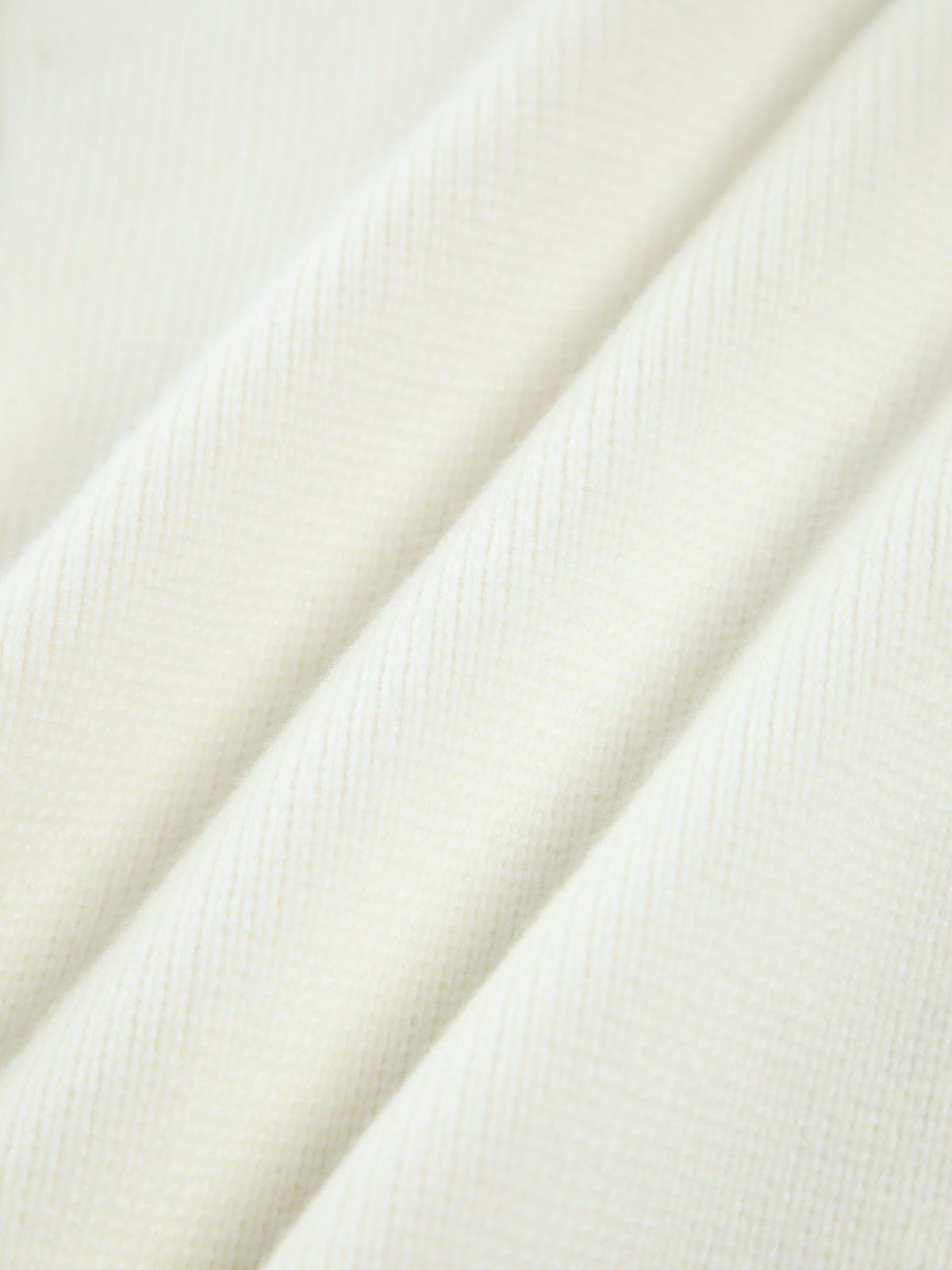 Close-up of cream soft-knit cardigan fabric texture with smooth knit surface