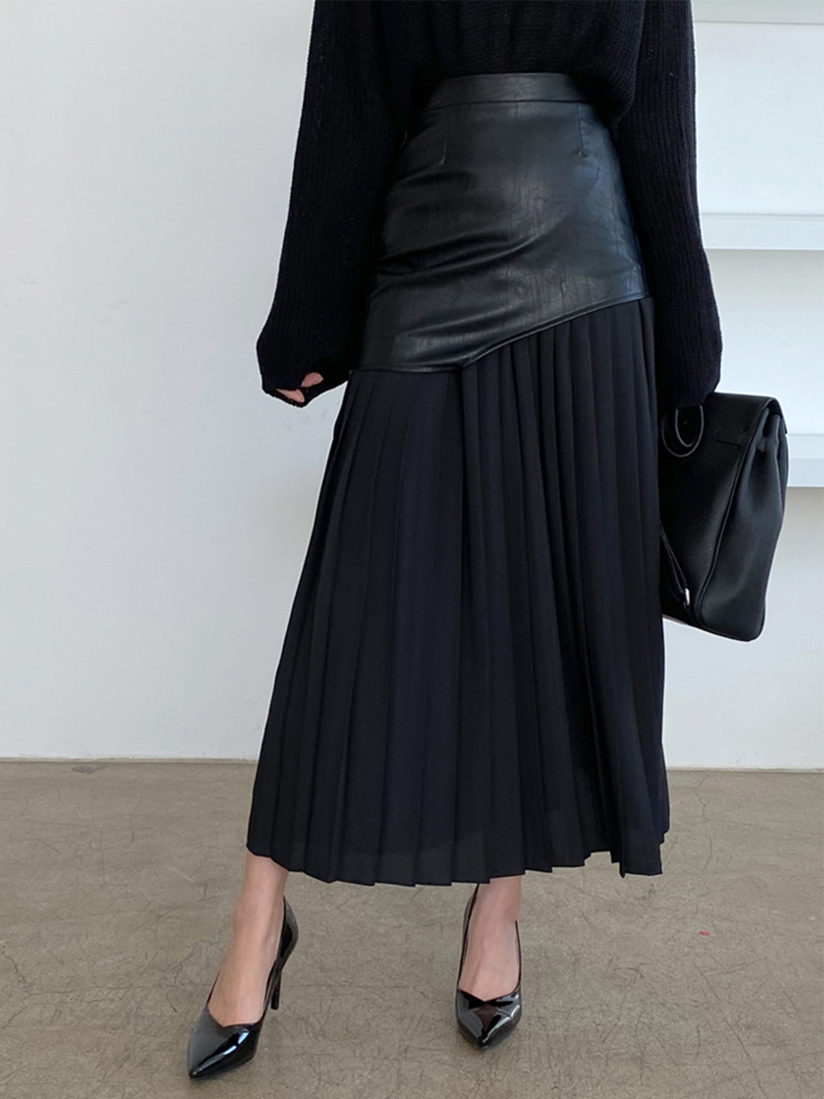 Black leather maxi skirt with pleated lower half and fitted waist overlay