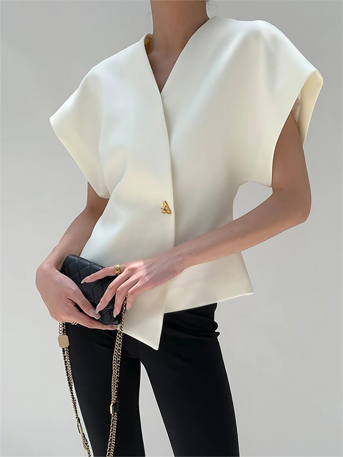 White crepe blouse with V-neck, cap sleeves, asymmetric gold button and peplum hem