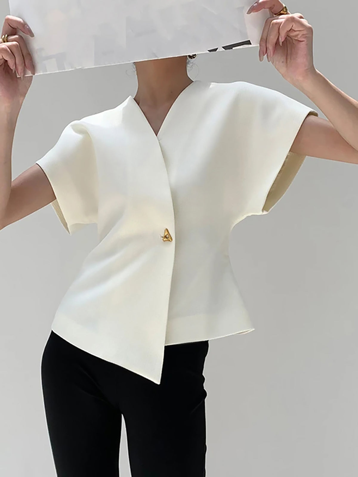 White crepe blouse featuring V-neck and cap sleeves with asymmetric gold button