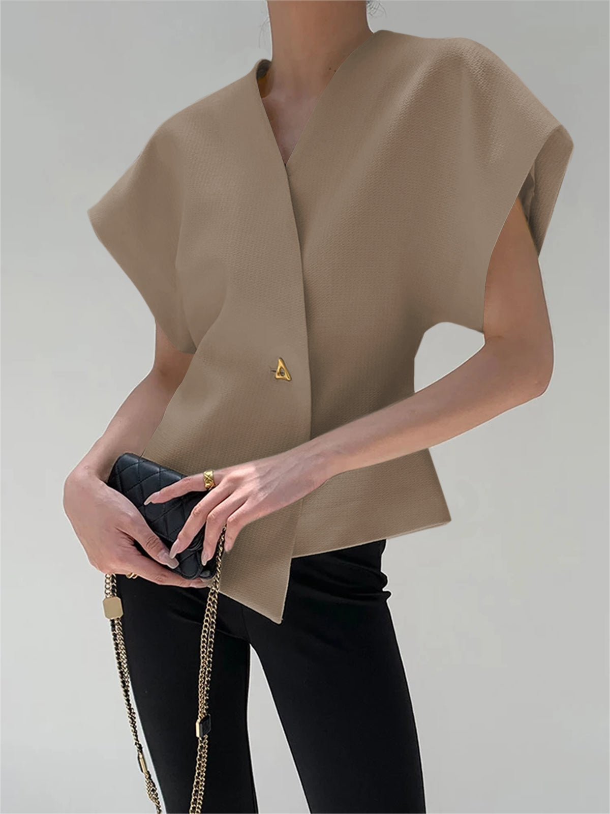 Beige crepe blouse with V-neck, cap sleeves, and an asymmetric gold button detail