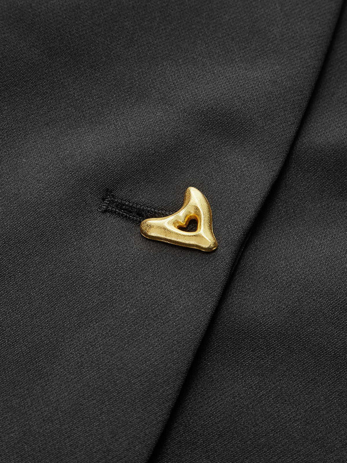 Close-up of black crepe blouse with gold asymmetric button on the V-neck