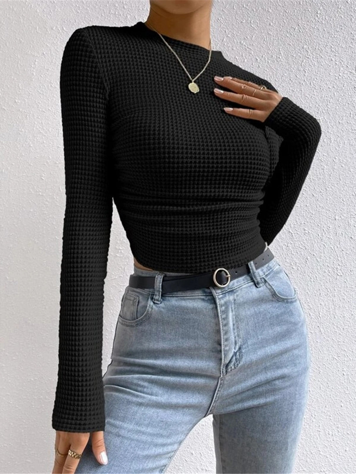 Black waffle-knit long-sleeve slim crop top with ruched hem and crew neckline.
