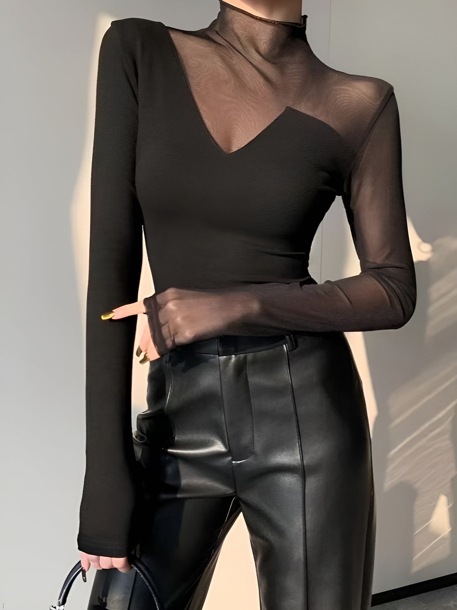 Black mesh long-sleeve top with mock neck and asymmetric sheer insert at bust