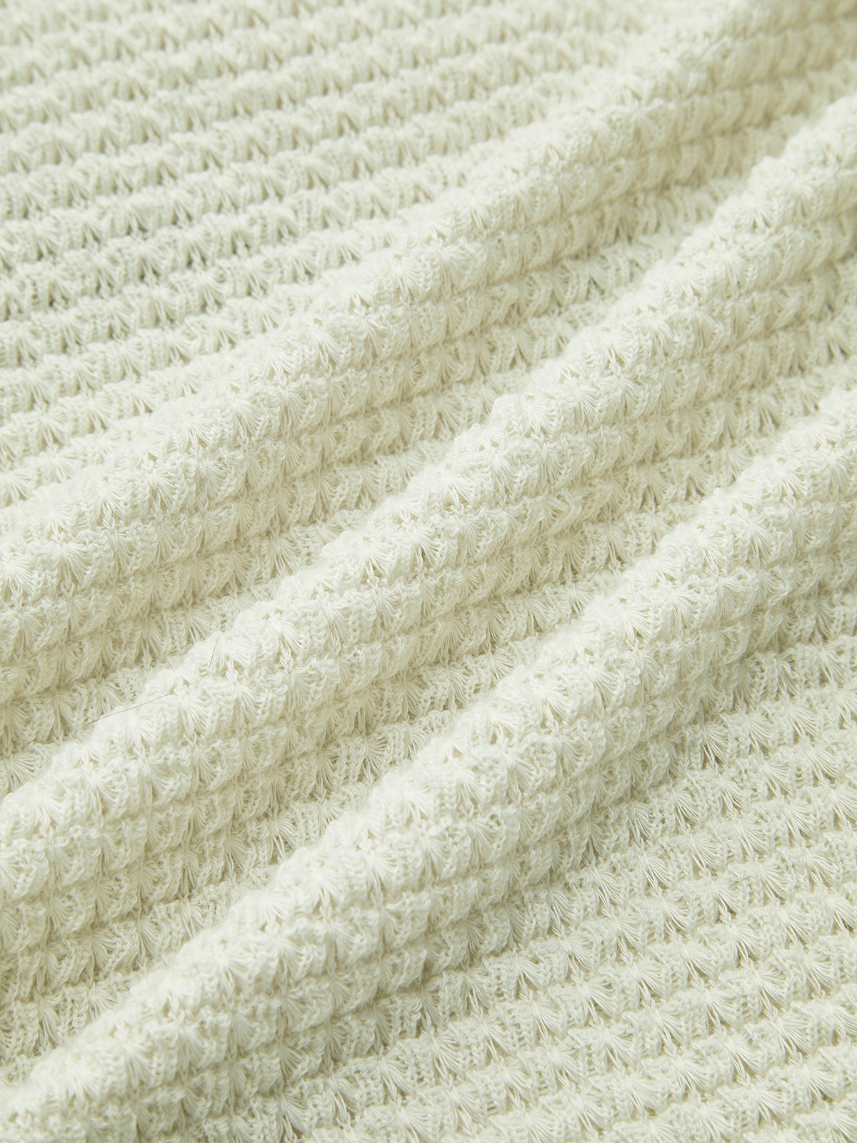 Light cream waffle-knit fabric close-up showing raised texture and knit ridges.
