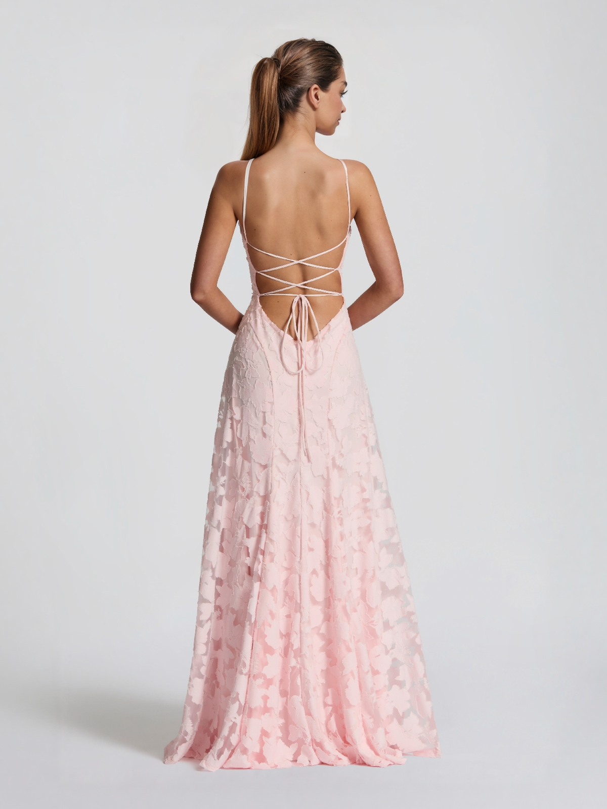 Pink satin maxi dress with spaghetti straps, open lace-up back, and floral overlay.