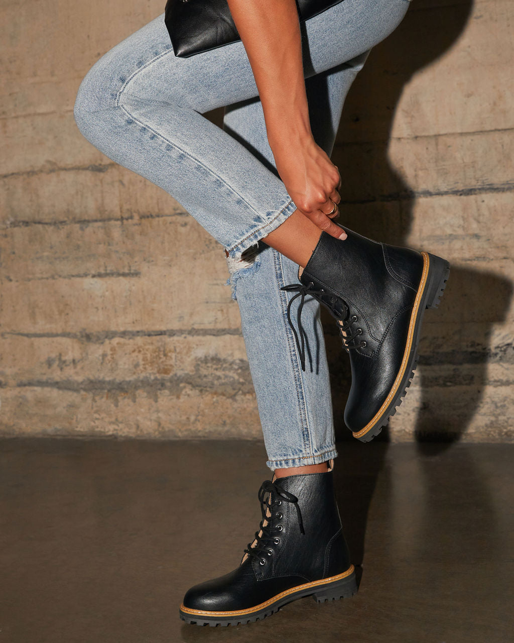 Black faux leather lace-up boot with yellow trim and rugged tread sole
