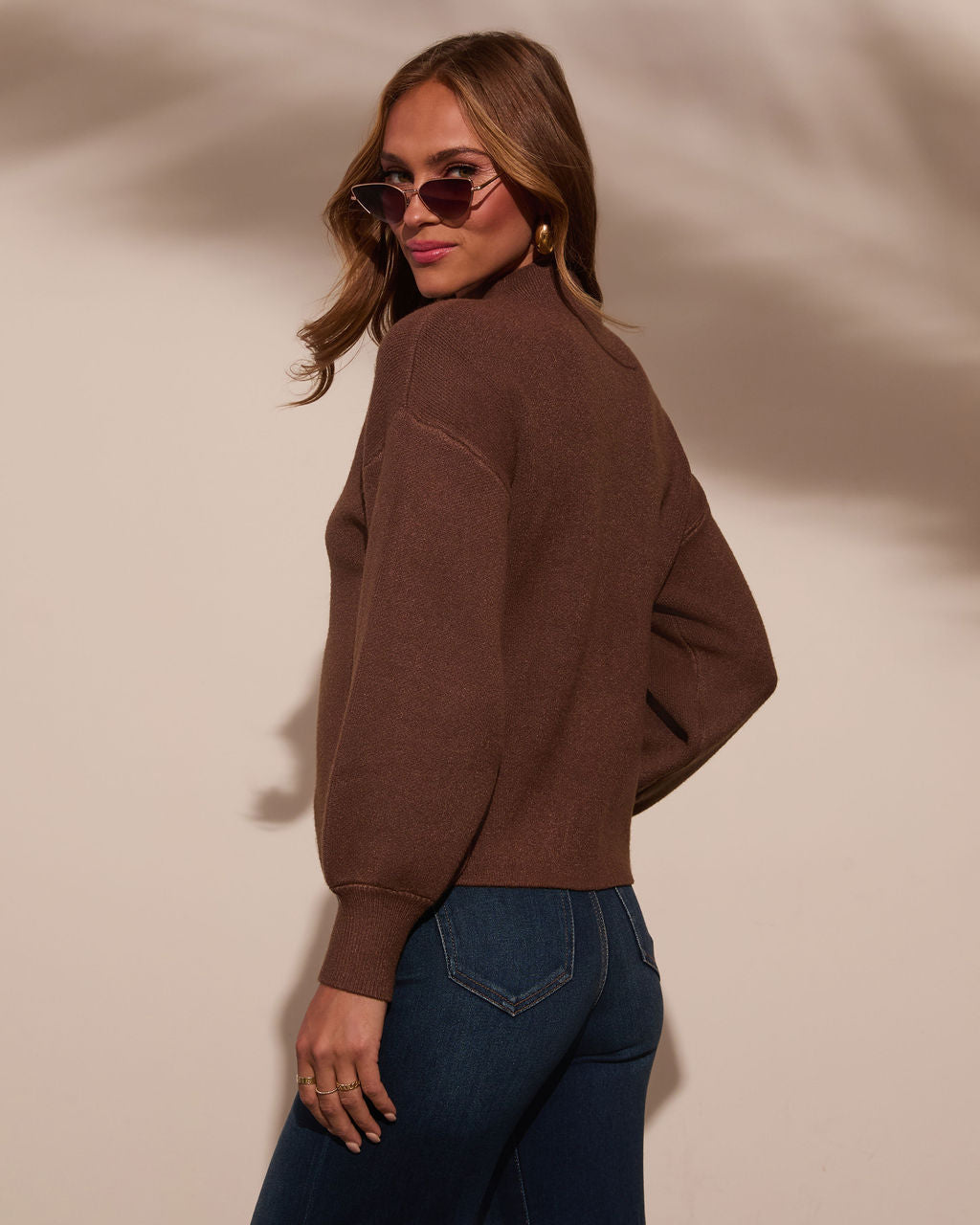 Mocha/brown mock neck sweater in a side view with long sleeves and ribbed cuffs.