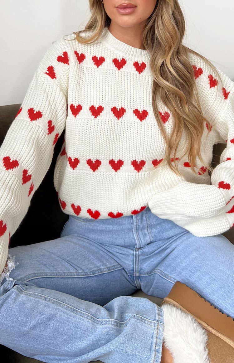 White knit jumper with red heart stripe pattern across chest, crew neck