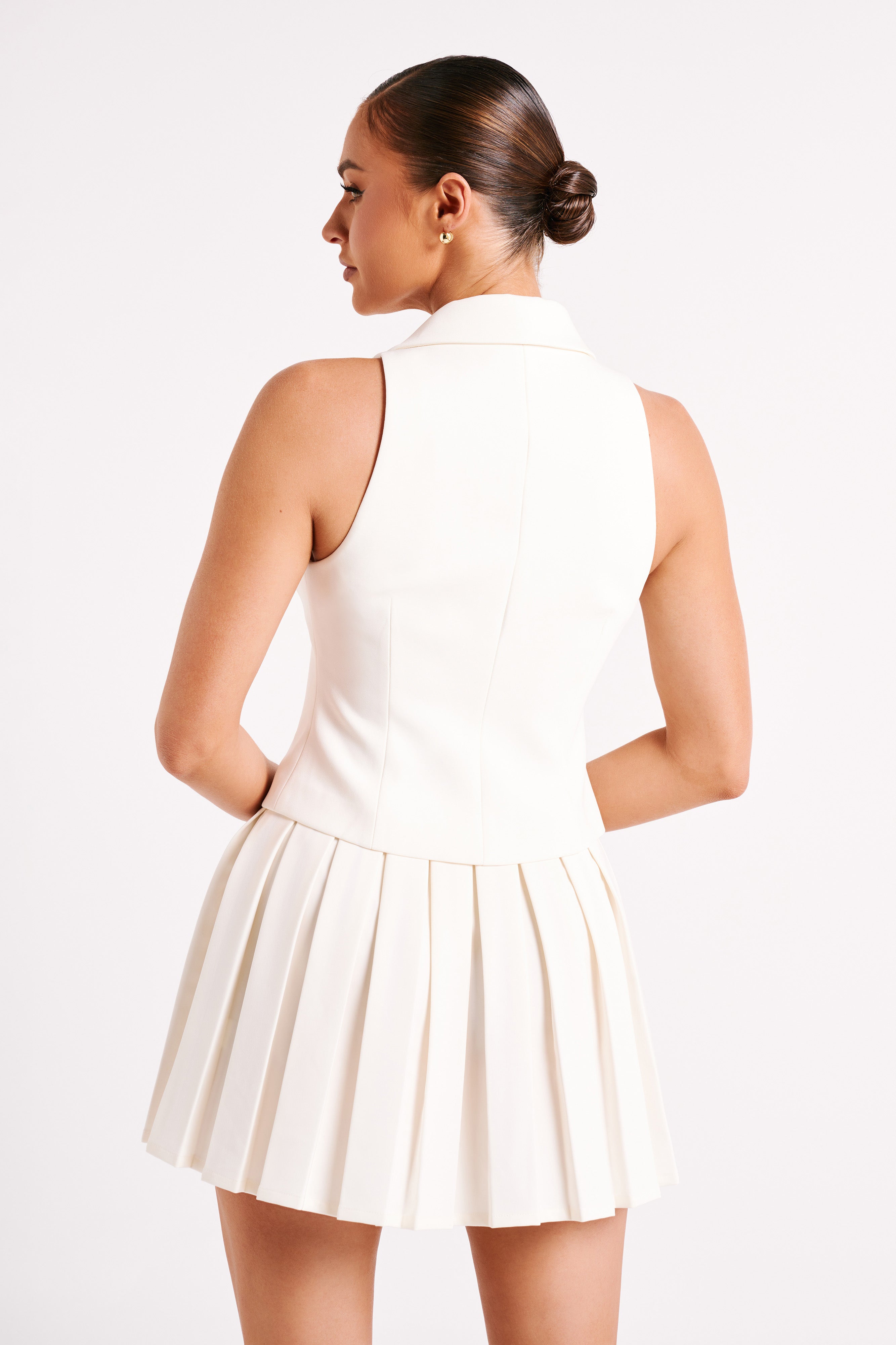 White sleeveless mini dress back view with high collar and pleated skirt