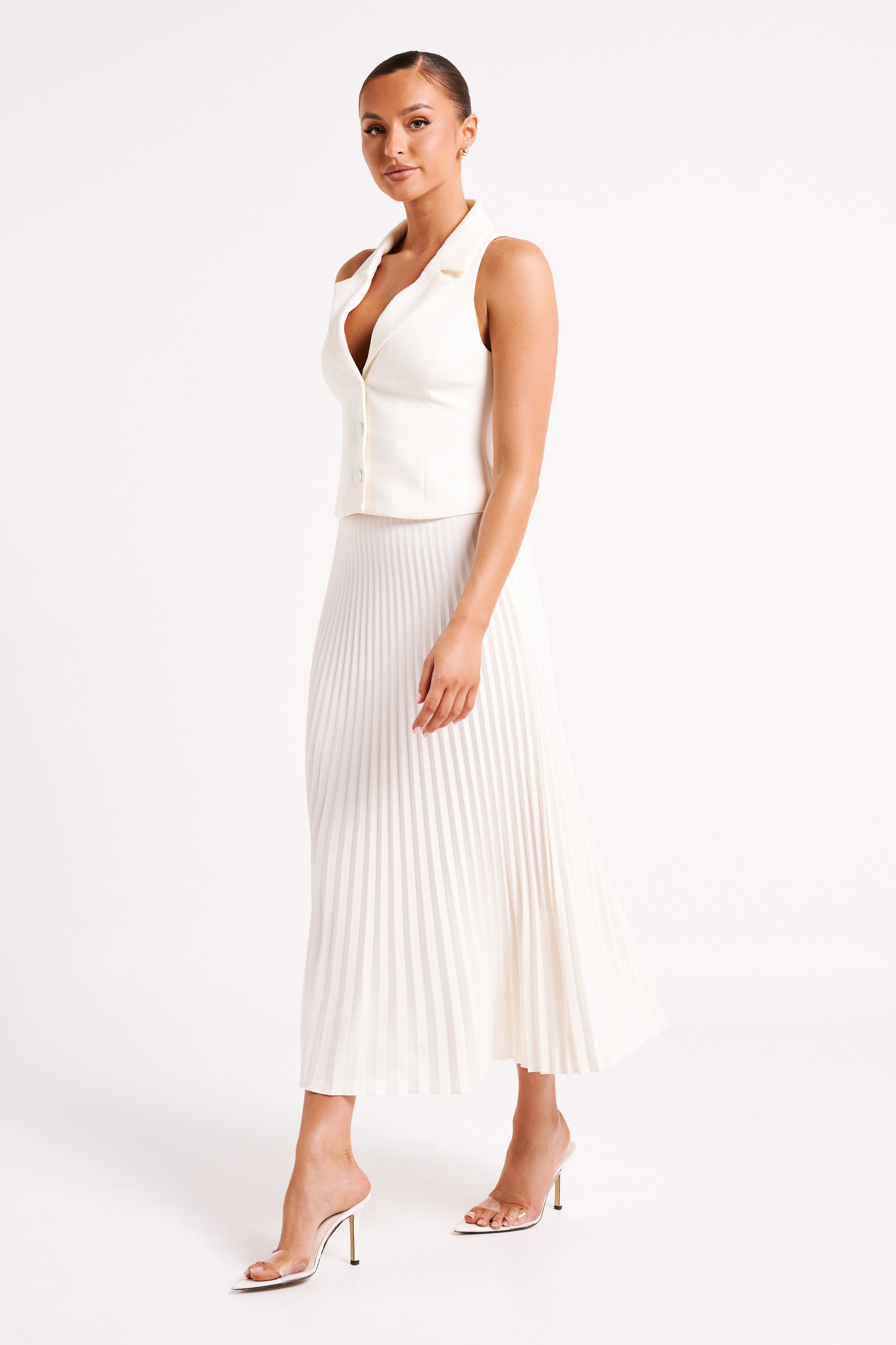 White sleeveless blazer mini dress with buttoned bodice and pleated skirt, side profile