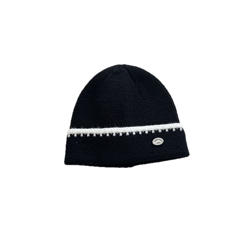 Black knit beanie hat with white striped band and small oval logo patch