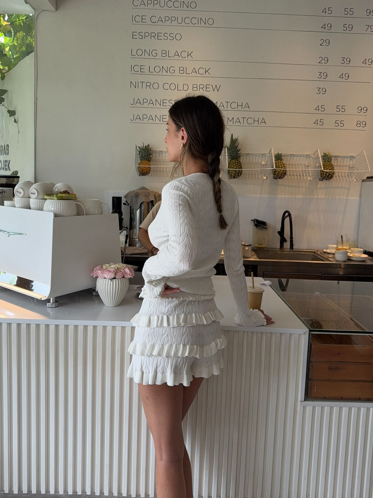 White knitted cardigan with long sleeves and tiered ruffle hem, side view