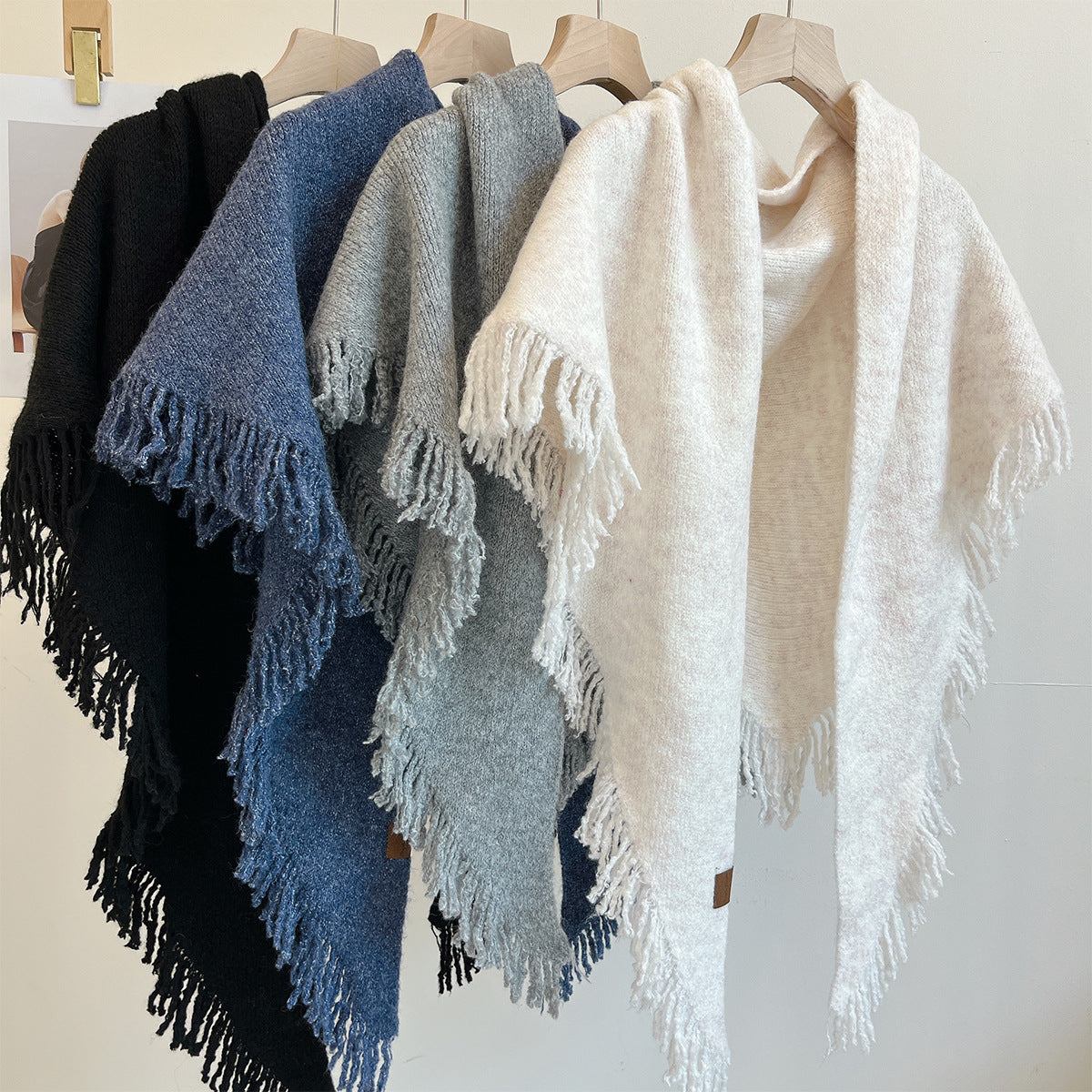 Cream large tassel triangle shawl with fringed edges, draped on hanger