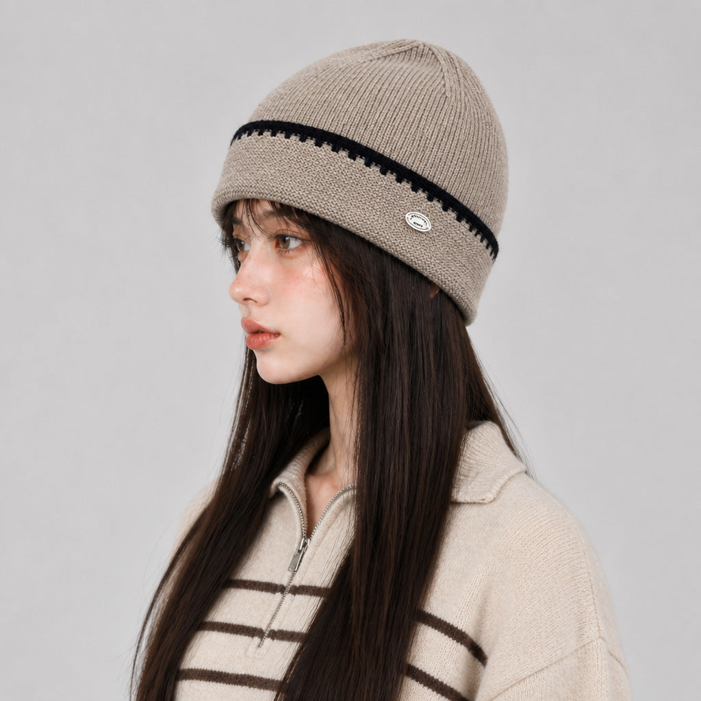 Khaki knit beanie hat with black striped band and small oval logo patch