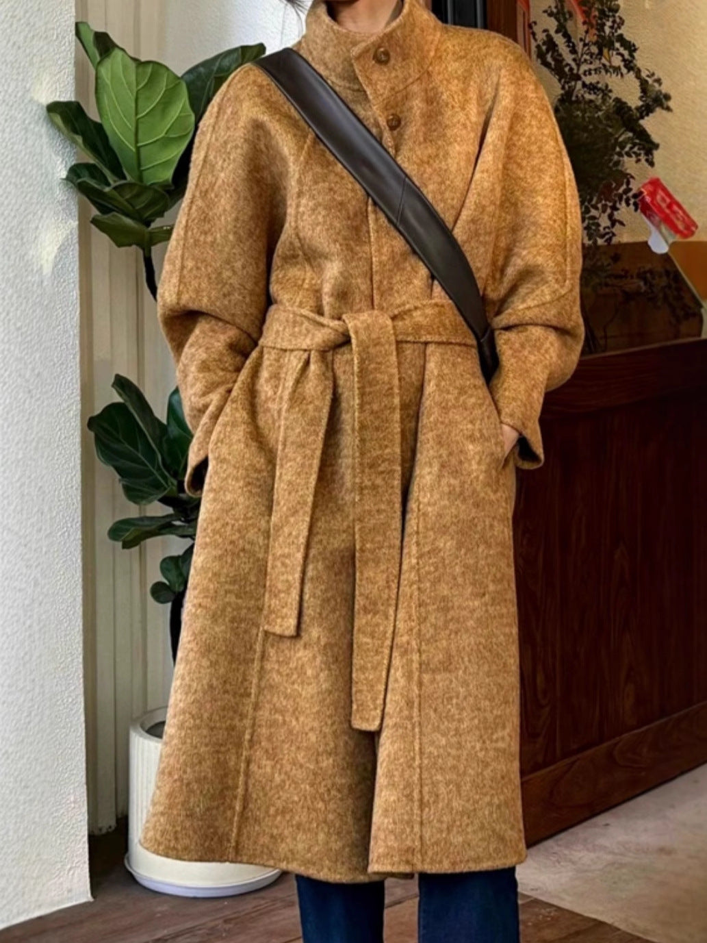Brown long wool coat with stand collar, button front, and fabric belt tie at waist