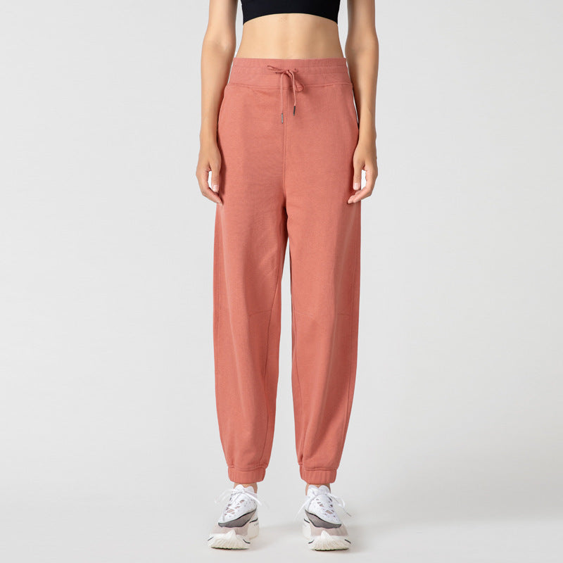 Brick-red jogger pants with drawstring waist, side pockets, and cuffed ankles