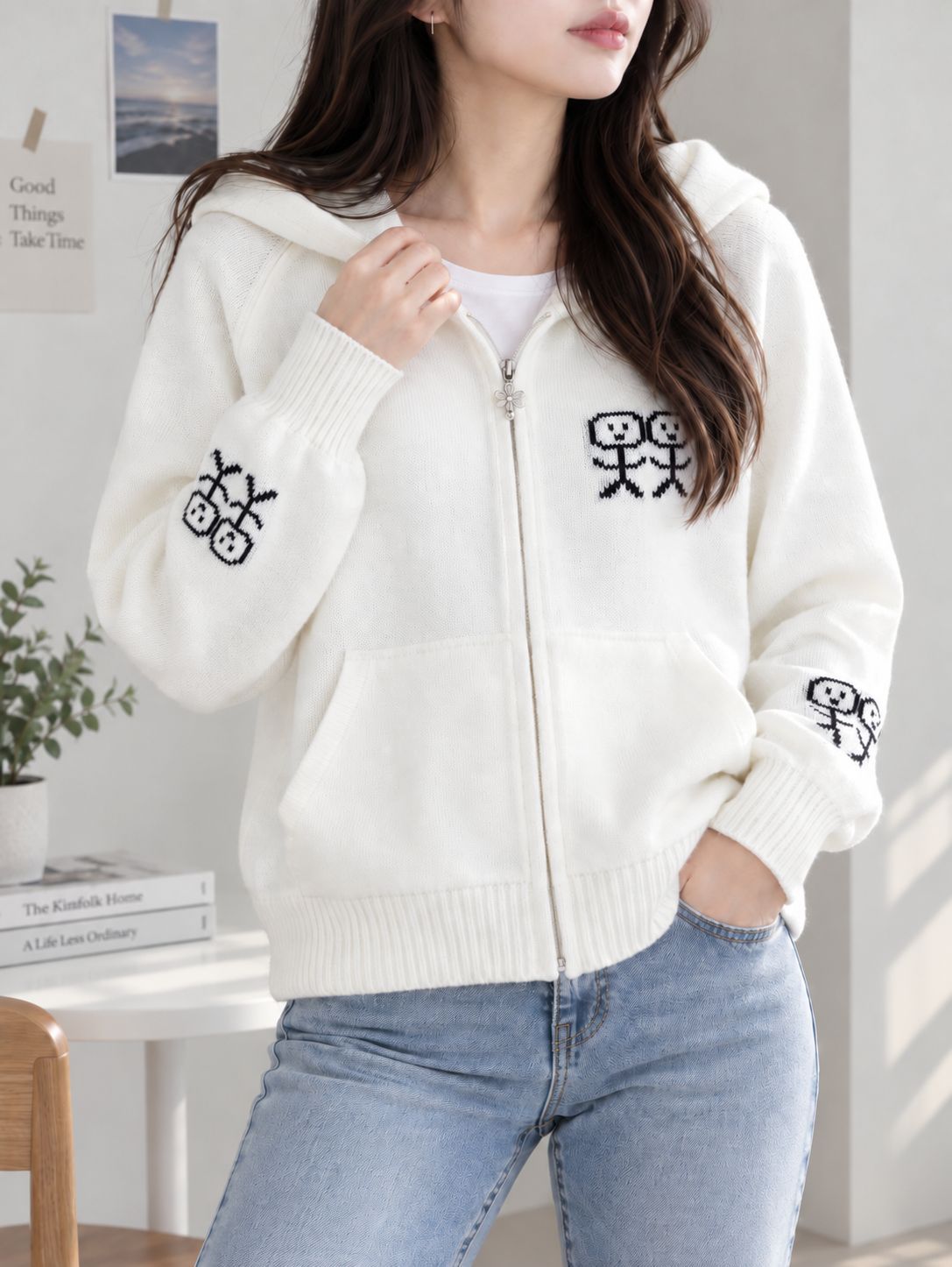 White zip-up hooded knit cardigan with graphic patches and front pockets.