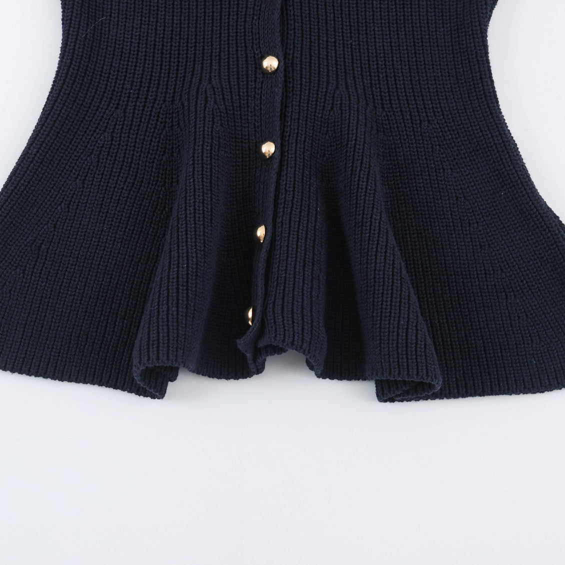 Dark blue chunky knit cardigan showing ribbed peplum flared hem and button front