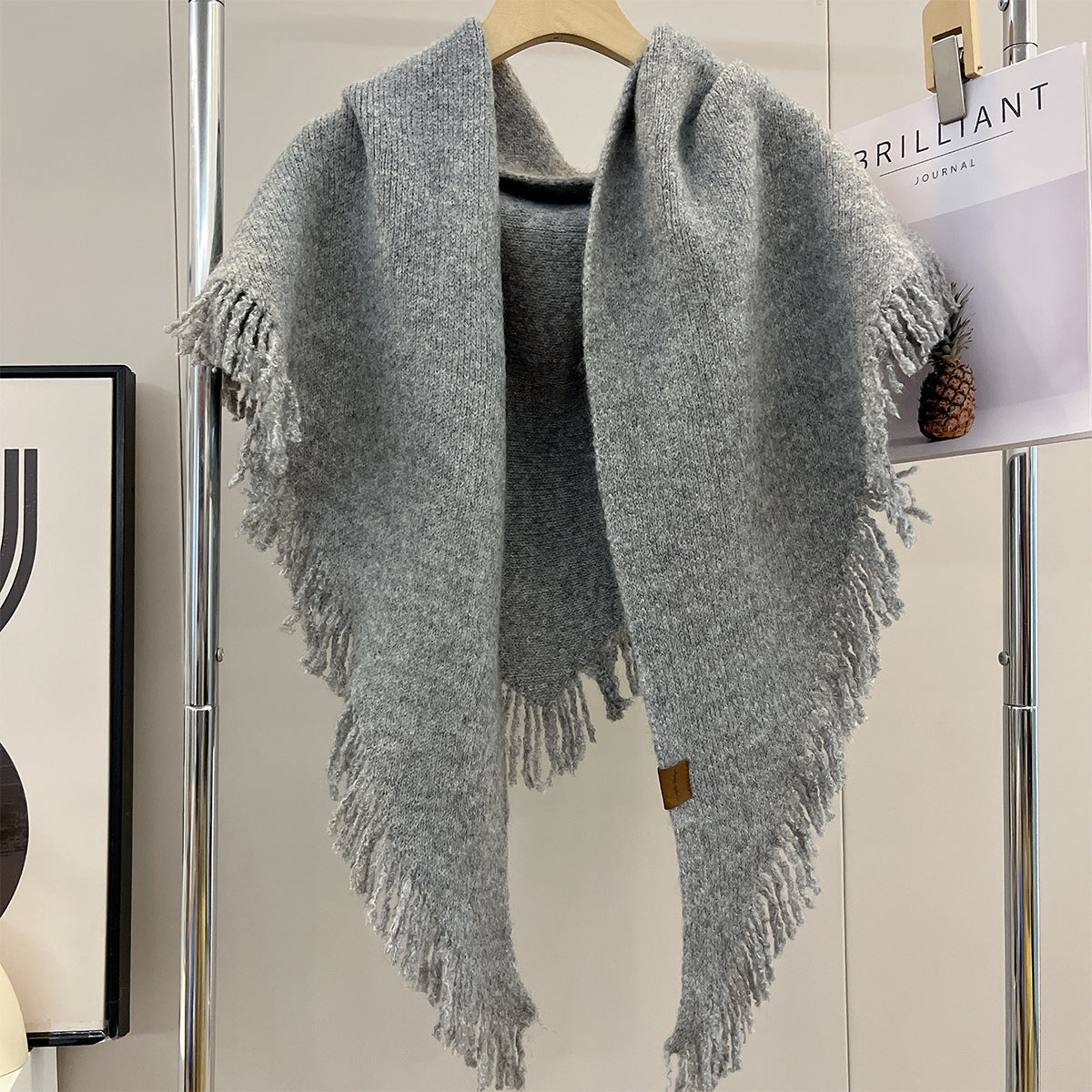 Gray marl triangle shawl with deep fringes on all edges, hanging on hook