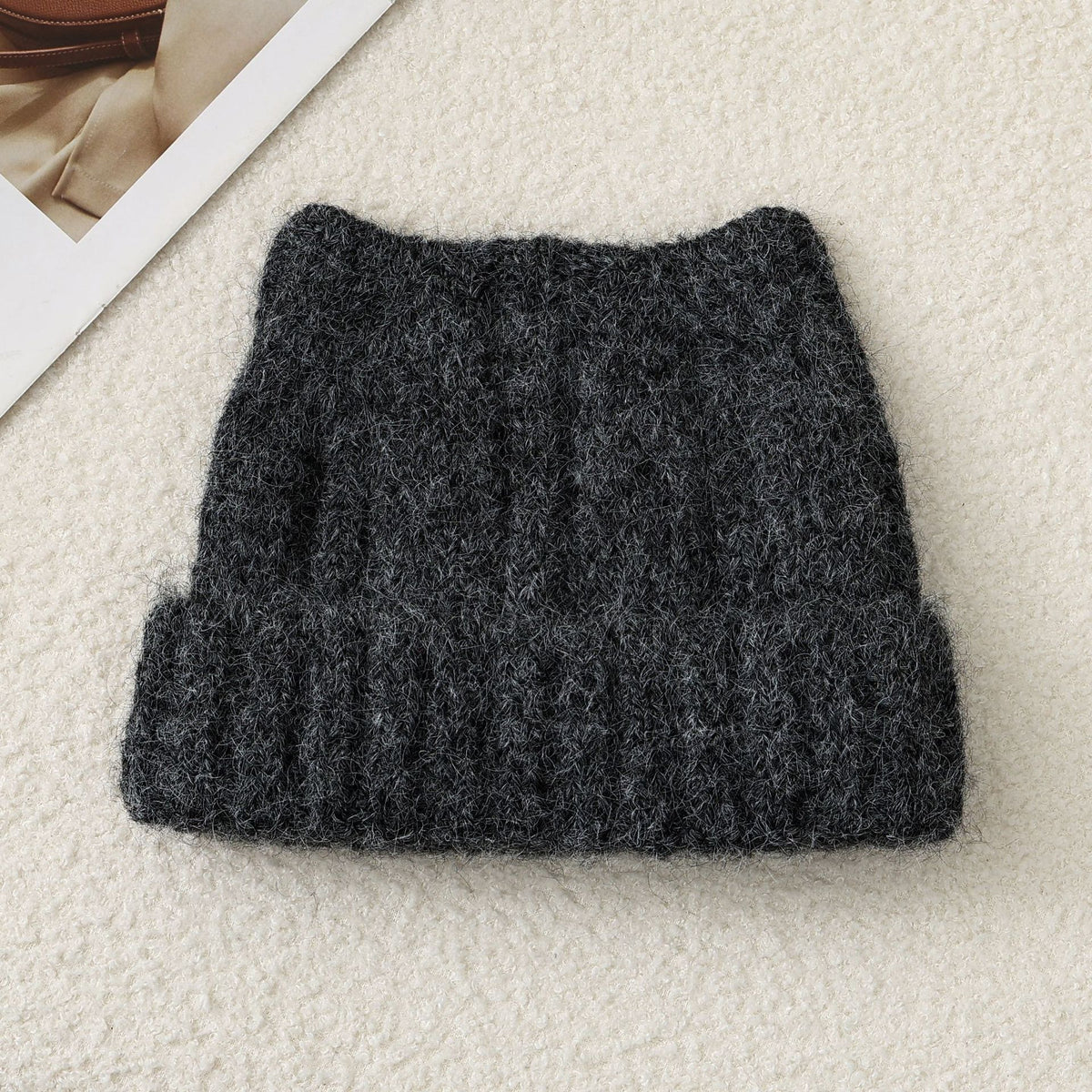 Dark gray cat-ear knit beanie, folded flat, fuzzy thick knit with ribbed band