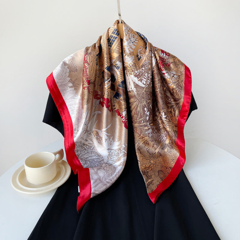 Brown silk square scarf with animal and leaf print, edged with red trim, draped.