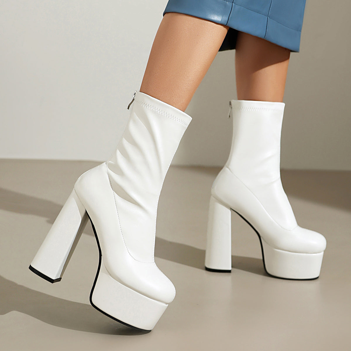 White platform mid-calf boots on model with chunky block heel and thick sole