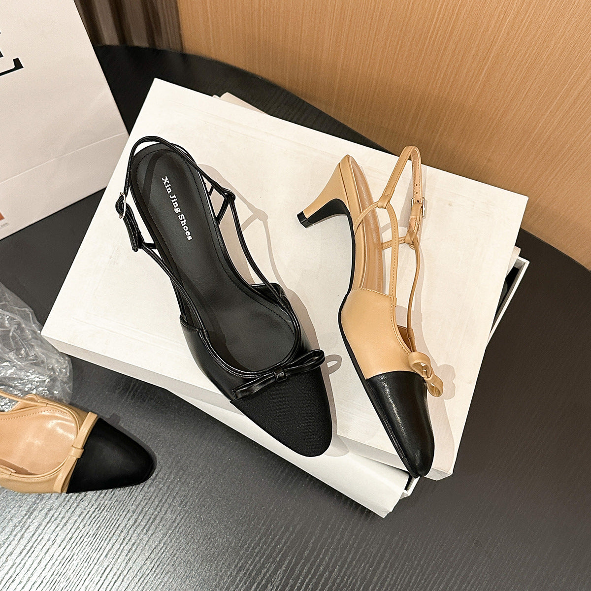 Pair of pointed-toe slingback flats, black and tan with bow strap detail