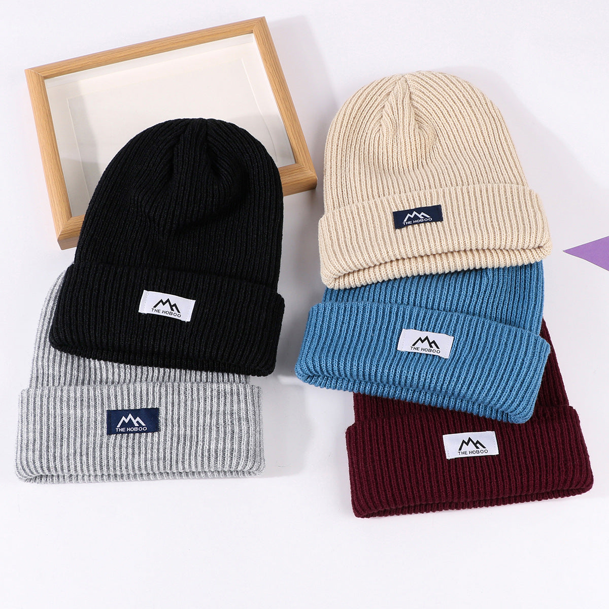 Knit beanie hats set in black, cream, light gray, blue, and burgundy, with logo patch