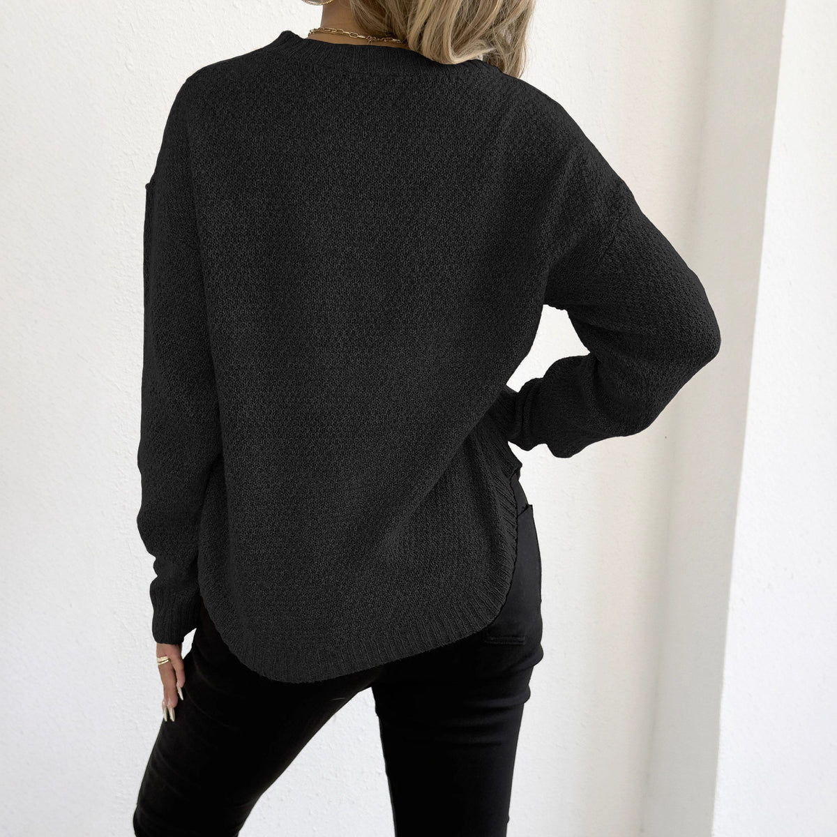 Black knit pullover sweater with round neckline and long sleeves, back view