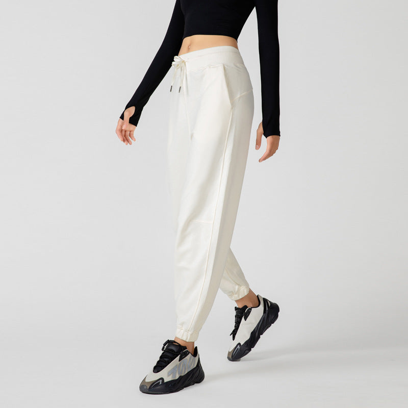 High-waisted ivory jogger pants with drawstring waist, side pockets, and cuffed ankles