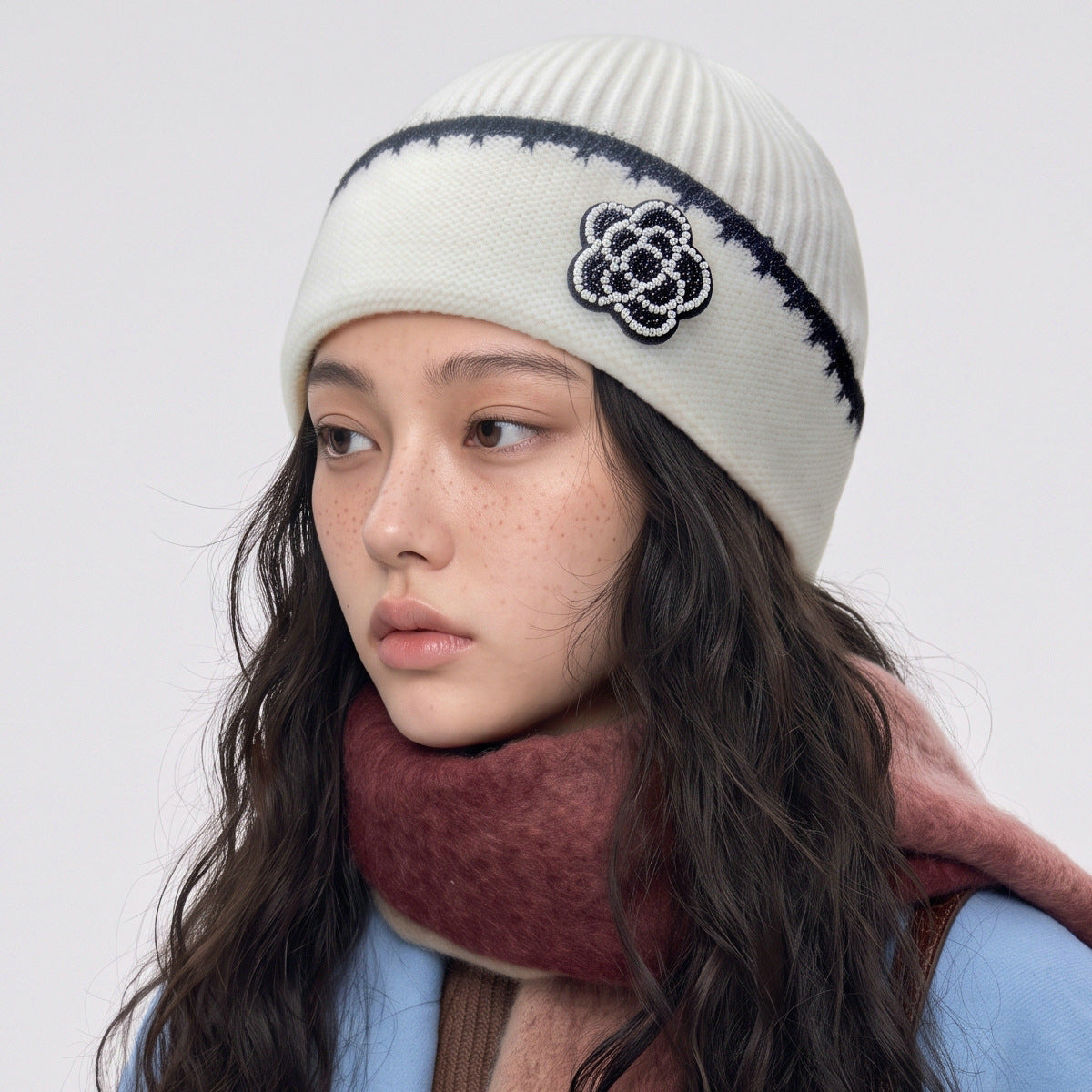 White knit beanie with black trim and flower applique