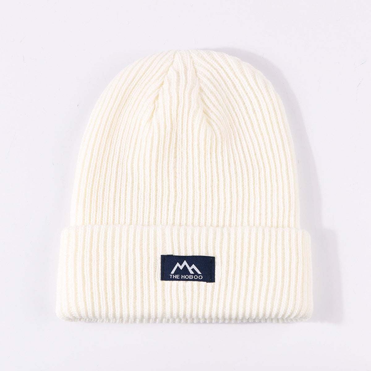 Milky white ribbed knit beanie with fold-up cuff and THE HOBOO logo patch