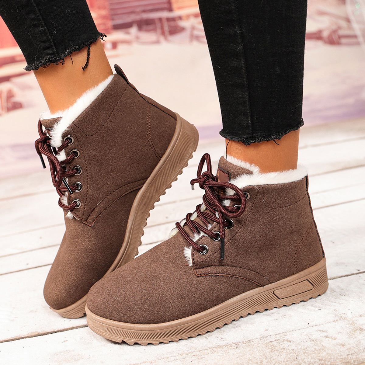 Brown fleece-lined lace-up ankle boots with padded collars and textured soles, worn as a pair.