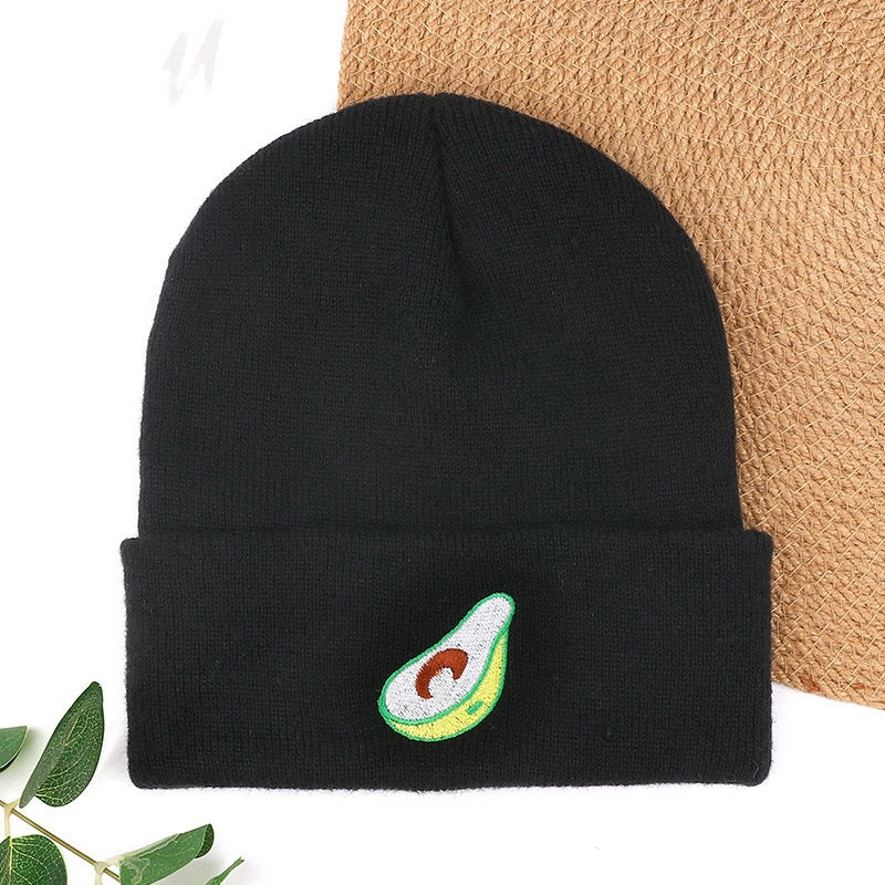 Black knit beanie with green avocado-like embroidery on cuff