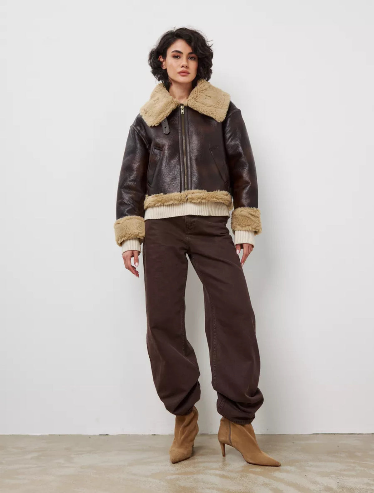 Women's short brown leather jacket with tan shearling collar and ribbed hem, zip front