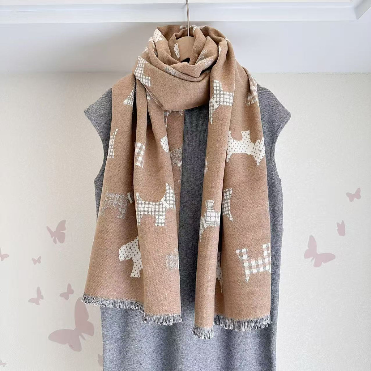 Tan scarf with dog motifs and fringed ends, draped around the neck